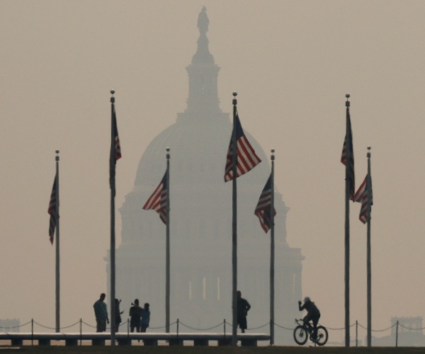 people in foreground in front of Washington monument in a smoky haze from Canadian wildfires