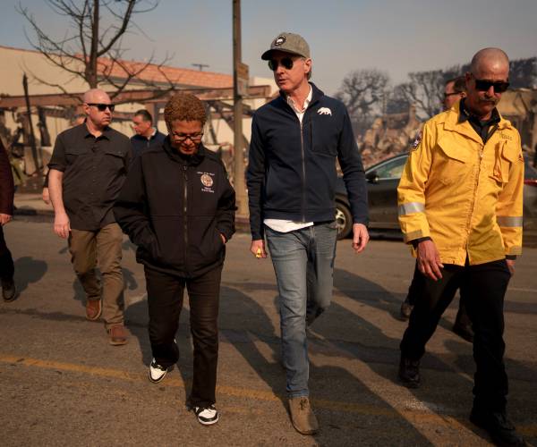 a group of people walking with burned out buildings in the background