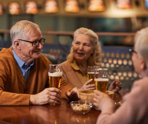 older man and women sitting at a table drinking beers