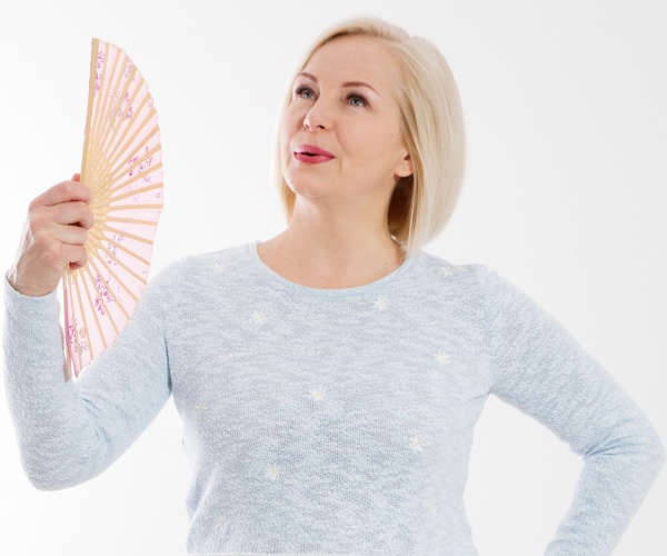 woman with hot flashes fanning herself