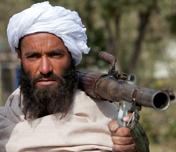 Taliban looks on with a gun on his shoulder