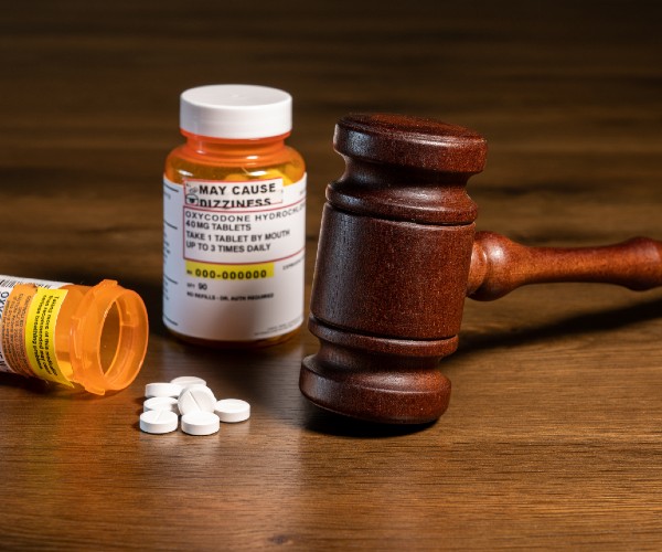 two bottles of oxycontin with pills lying on the table beside a judges gavel