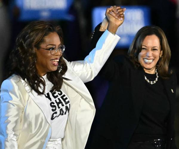 oprah winfey and kamala harris holding uplifted hands and smiling