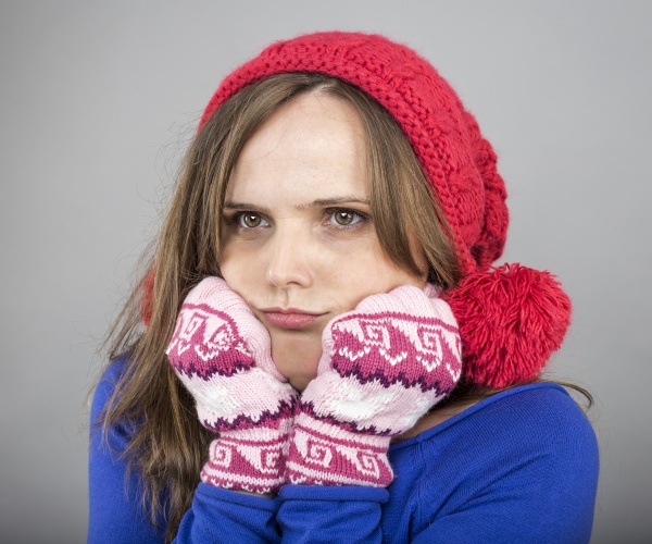 woman looking cold, wearing wool hat and mittens