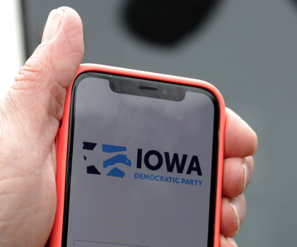 a hand holding a smartphone showing the words iowa democratic party