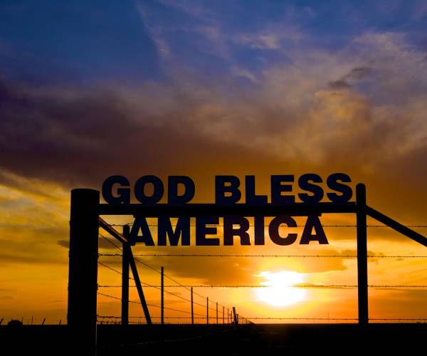 god bless america on a fence against a sunset