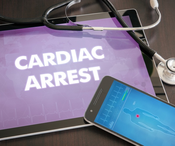 tablet screen says 'cardiac arrest' and smartphone screen shows illustration of body with heart highlighted