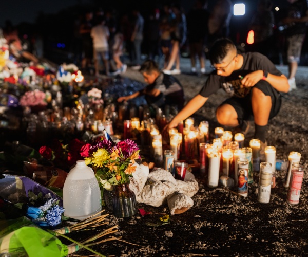 mourners lay bottles of water on the ground at a makeshift memorial