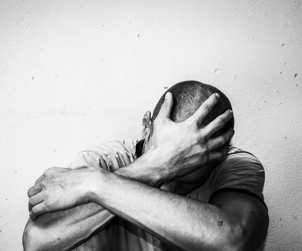 man crouching down with head in hands in depression